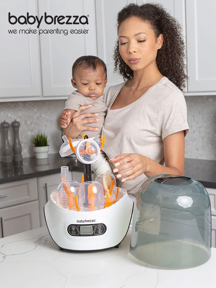 a mother holding a baby while taking a bottle out of the baby brezza sterilizer and dryer