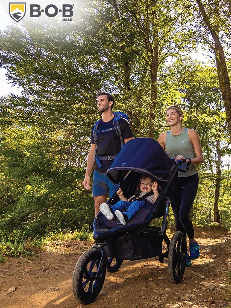 a man and woman on a hiking trail pushing a baby in the bob alterrain stroller