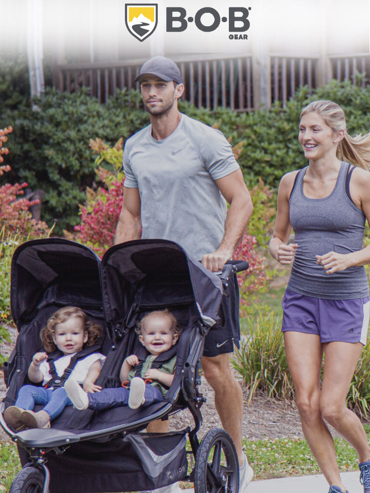 a mom and dad jogging with two toddlers in the bob revolution flex 3.0 double stroller