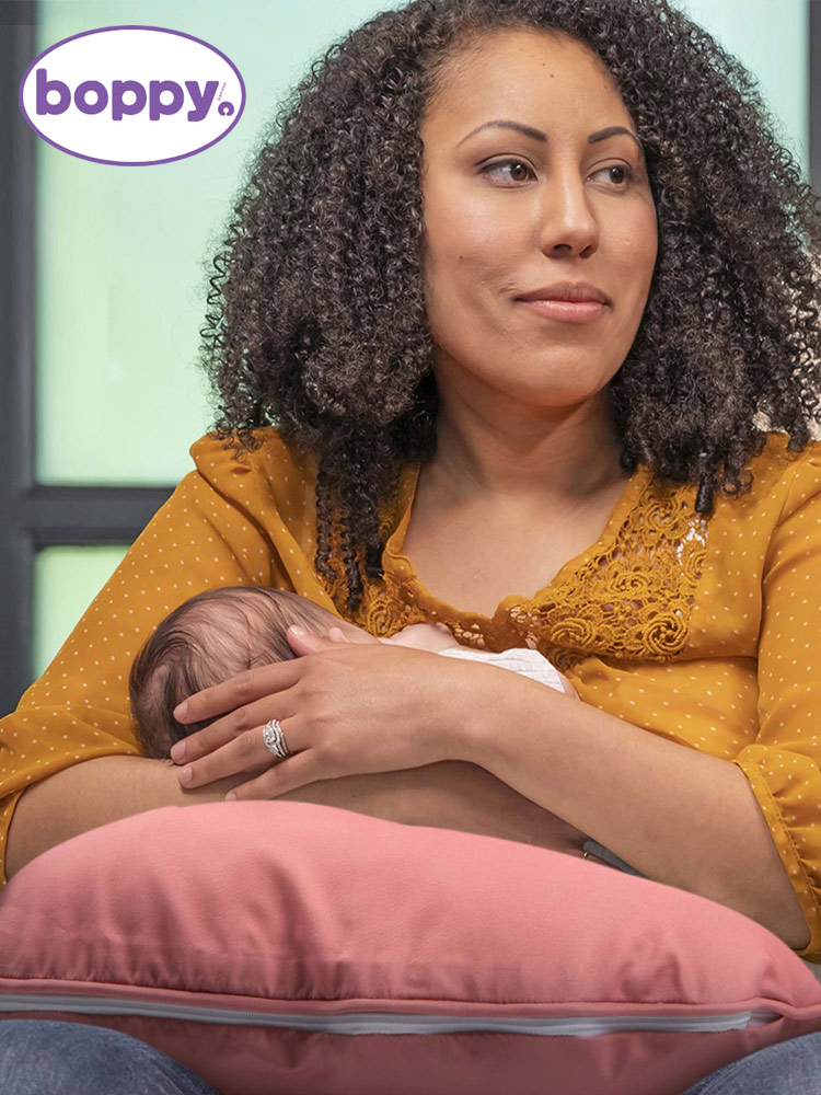 a woman breastfeeding a baby on the Boppy Nursing Pillow
