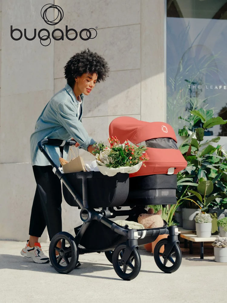 a woman pushing the bugaboo donkey 5 stroller with storage of flowers and groceries
