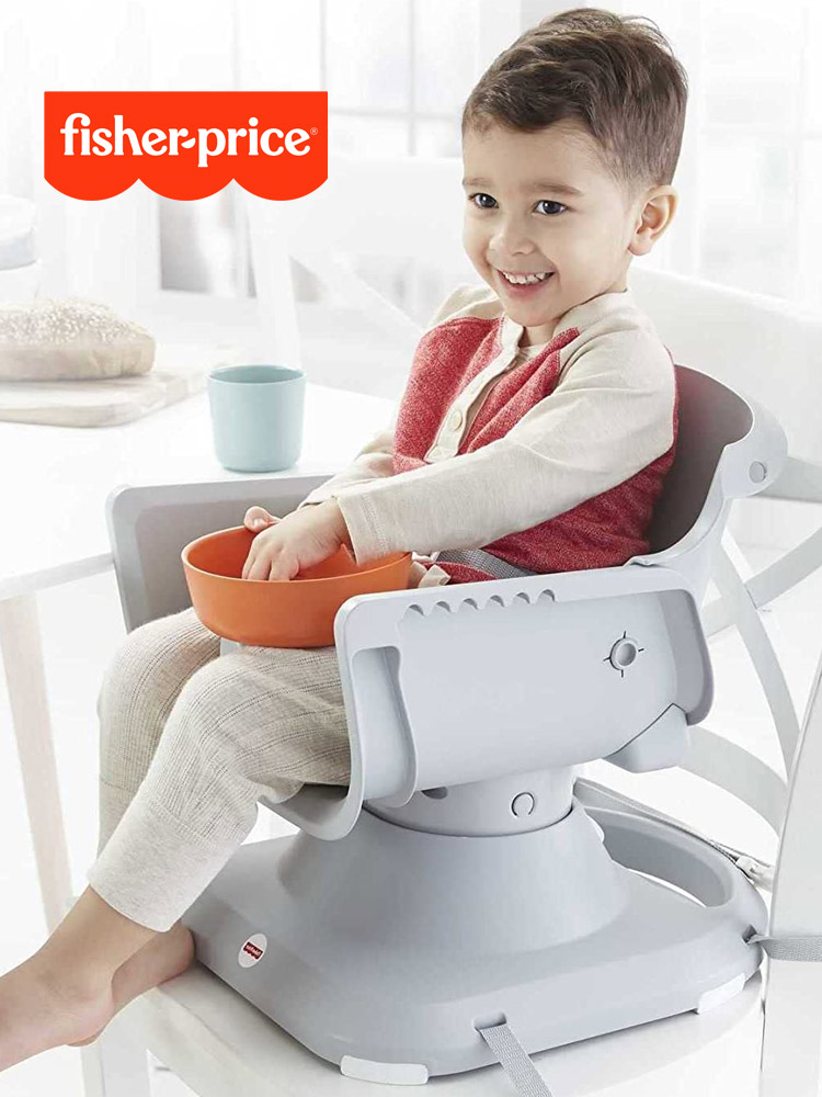 a toddler boy sitting in the fisher price spacesaver high chair while eating from a bowl of food