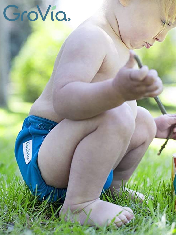 a toddler playing outdoors wearing a grovia one all-in-one cloth diaper