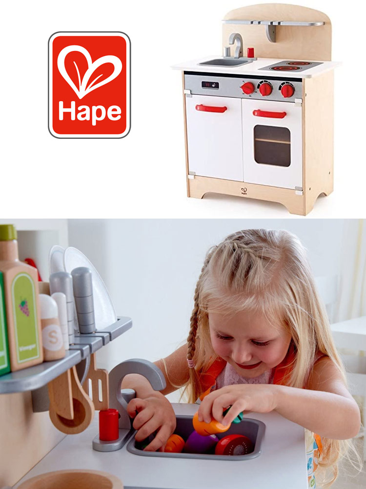a girl playing with pretend fruits and vegetables in the hape wooden kitchen set