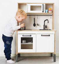 a boy playing with the ikea duktig play kitchen