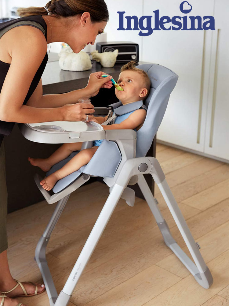 a mom leaning down and spoon feeding a baby sitting in the inglesina my time high chair
