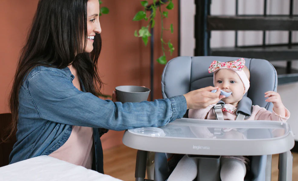 mom feeding a baby who is sitting in the inglesina high chair