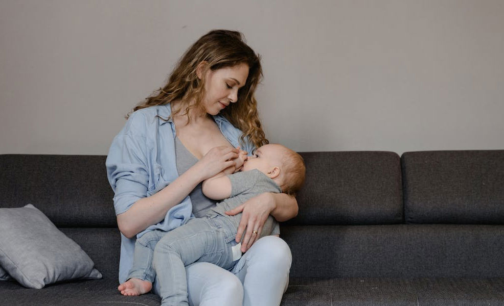 mom sitting on couch and breastfeeding baby with nursing bra