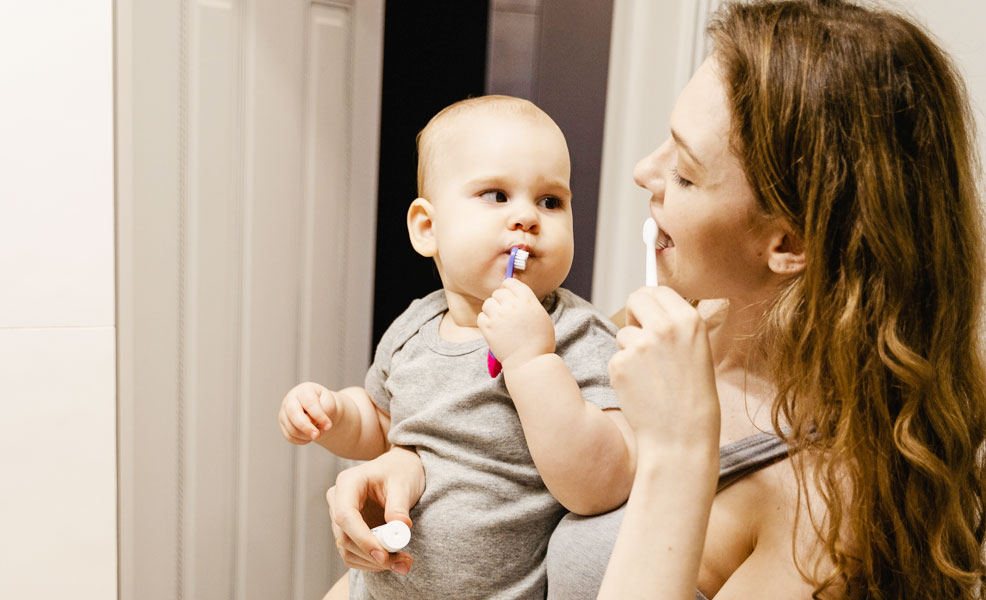 mom and baby brushing teeth together in the bathroom