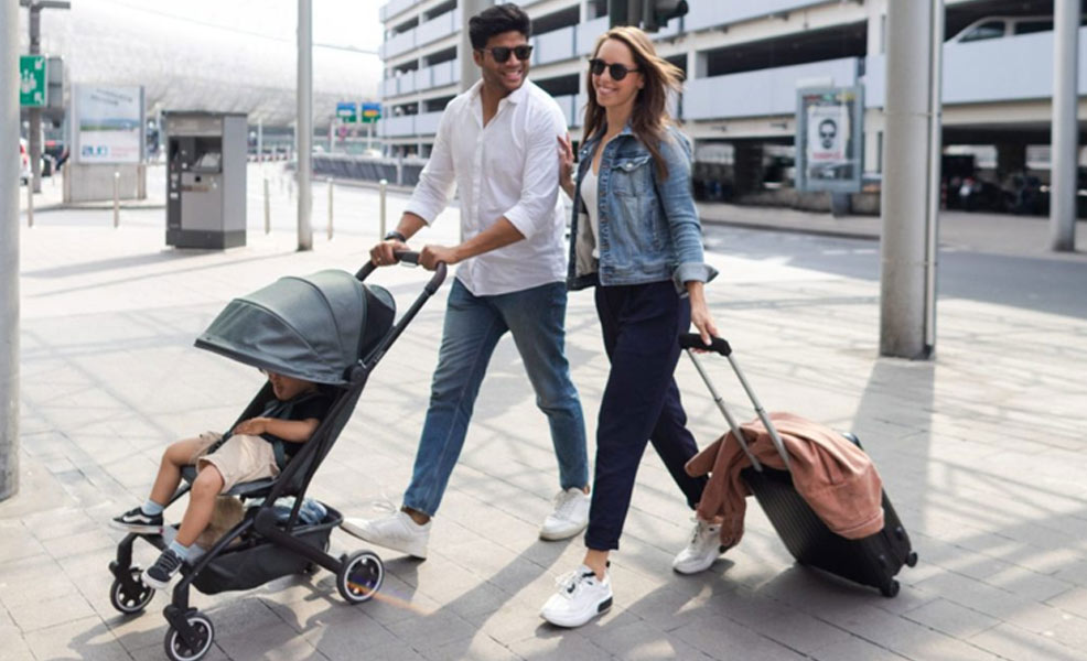 parents leaving the airport with a baby in a travel stroller