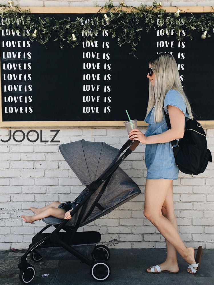 a woman pushing a joolz aer stroller against an urban background