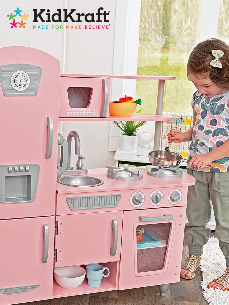 a girl preparing pretend food on the stove of a kidkraft Vintage play kitchen