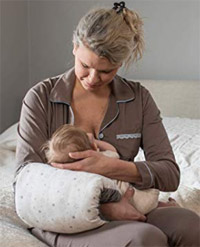 a woman breastfeeding a baby on the Lansinoh Nursie Pillow