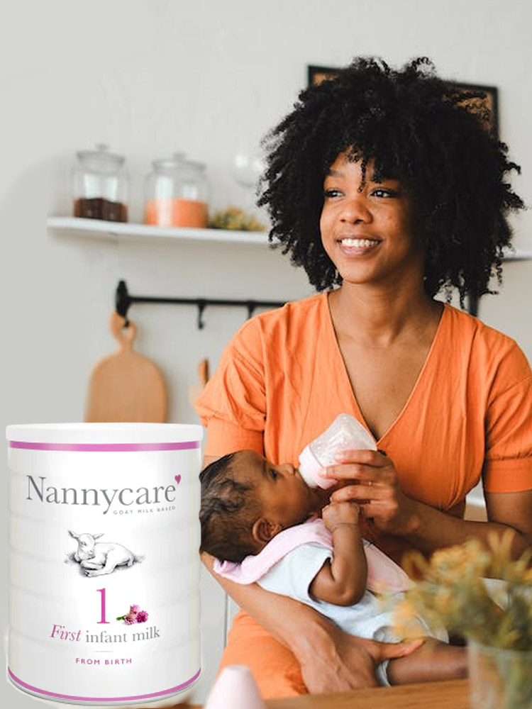 mom standing in kichen feeding baby with a bottle of nannycare goat milk formula