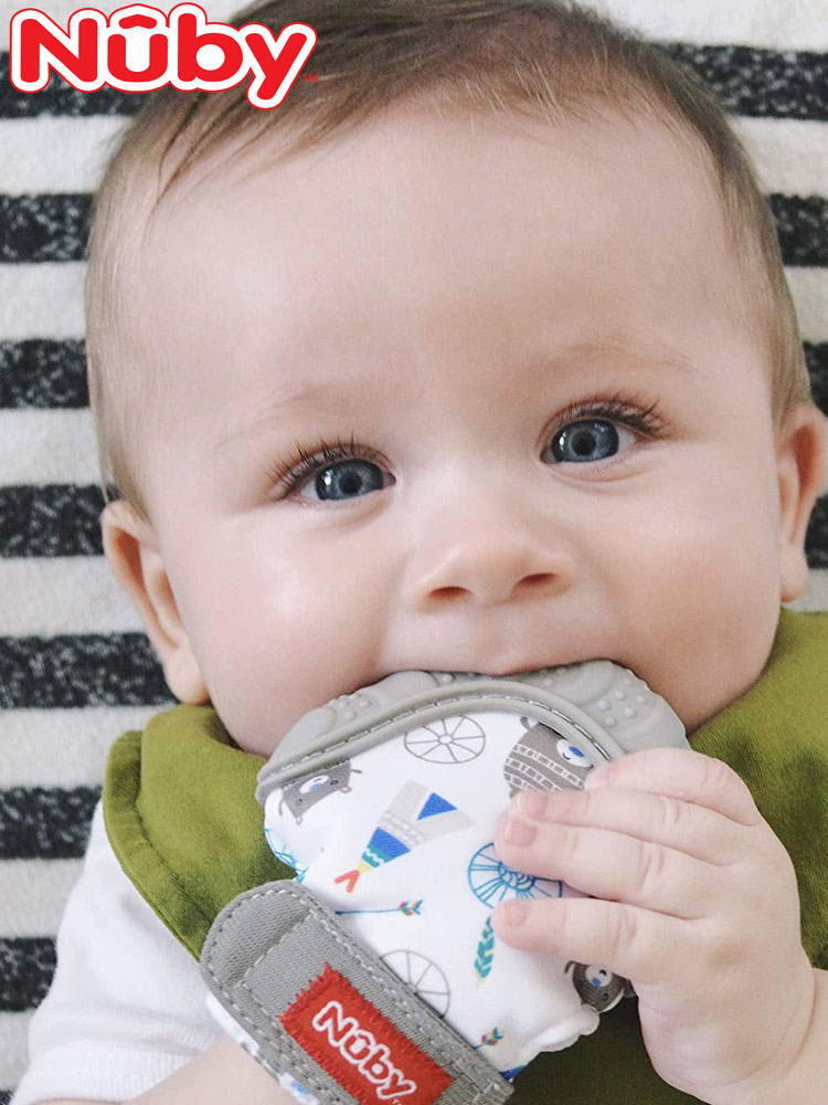 a happy baby chewing on the nuby mitten teether