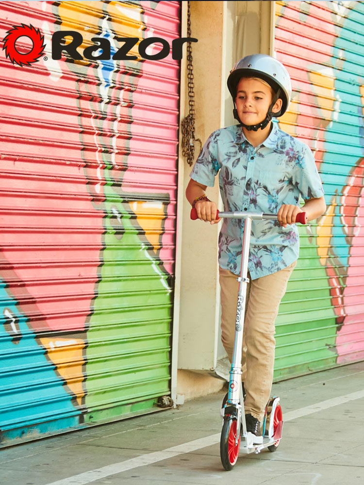 a young boy riding a razor a5 scooter in an urban background