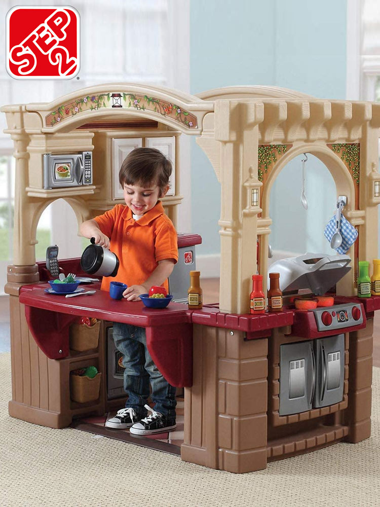 a boy preparing a pretend cup of coffee on the counter of the step2 grand walk-in play kitchen