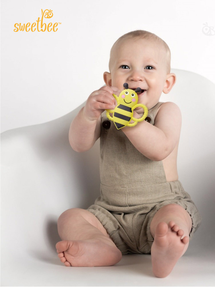 a smiling toddler chewing on the buzzy bee teething toy
