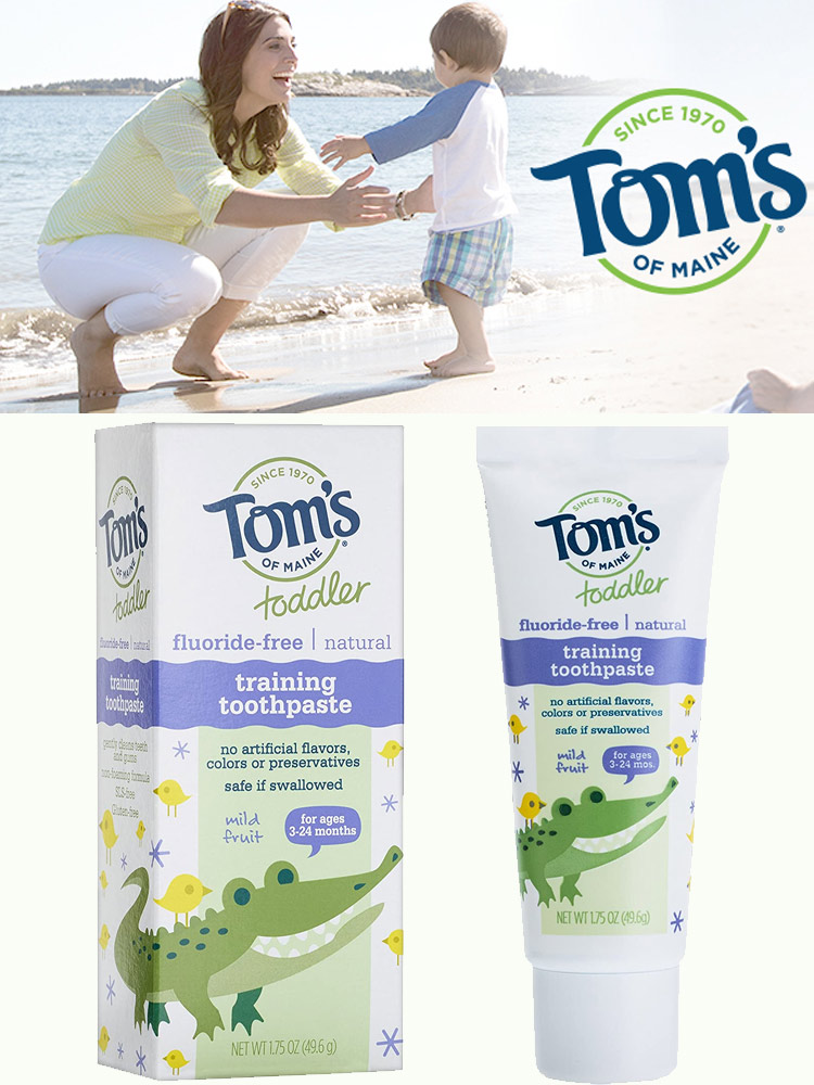 a box and tube of toms natural training toothpaste and a mom playing with baby on beach