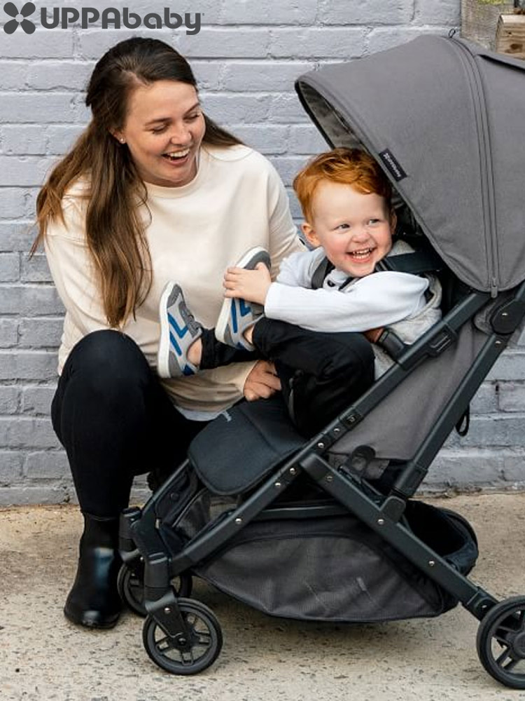 a mom buckling a toddler boy sitting in the uppababy minu v2 stroller