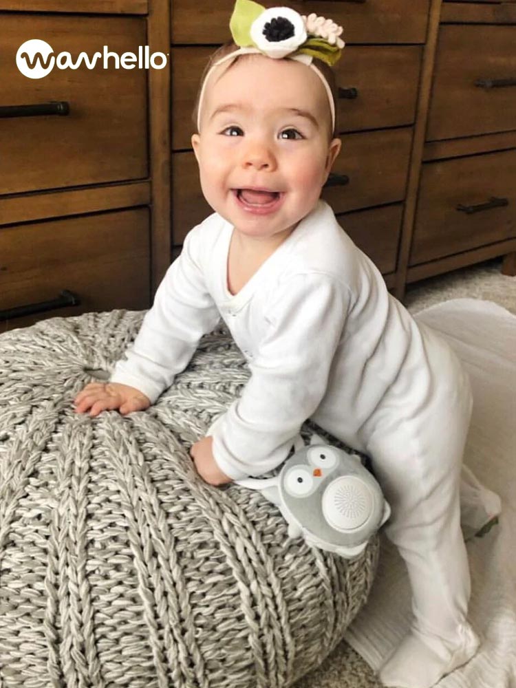 a smiling baby holding the wavhello soundbub white noise machine