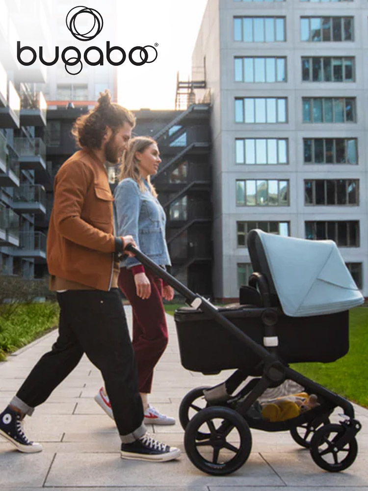 parents pushing a baby through an urban environment in the bugaboo fox stroller