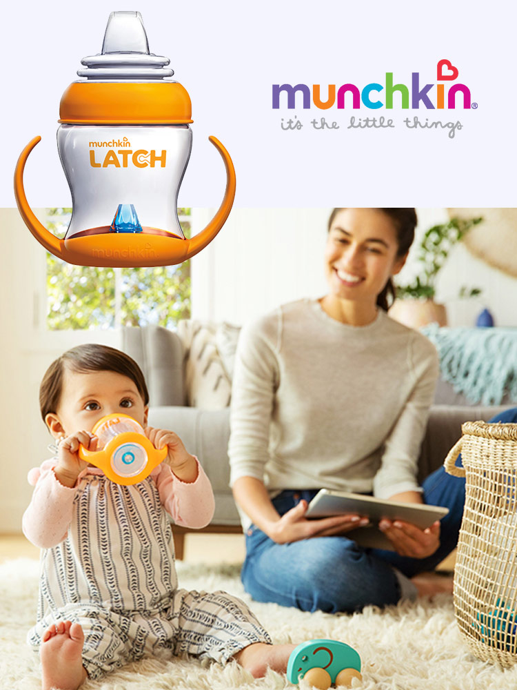 a toddler drinking from the munchkin latch transition cup while a mom watches in the background