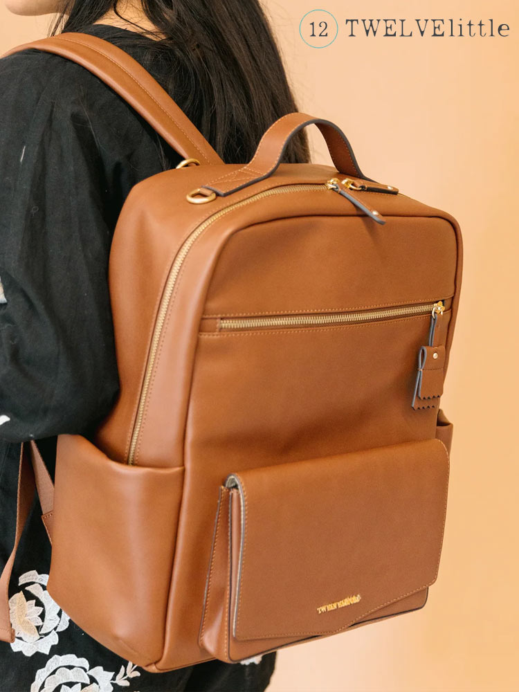 a woman wearing a brown leather twelvelittle peek-a-boo backpack diaper bag