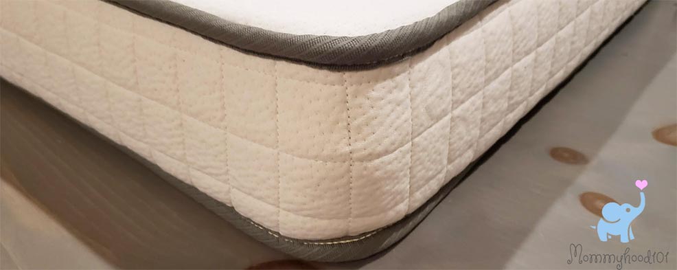 a close up photo of the high quality stitching on the avocado crib mattress