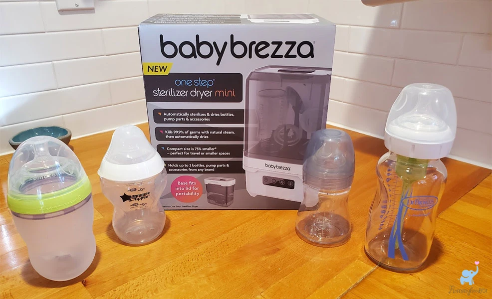 baby brezza sterilizer dryer mini on counter with assorted baby bottles