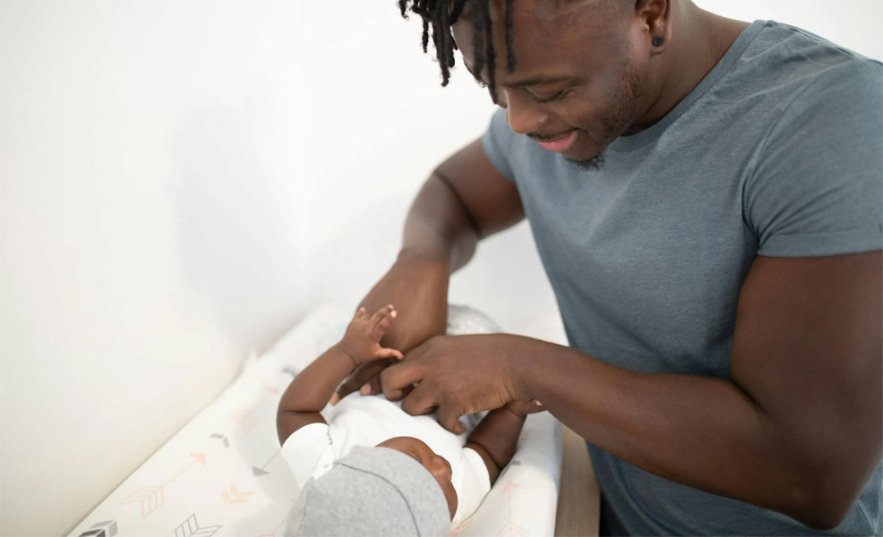 baby diaper change on changing pad with dad