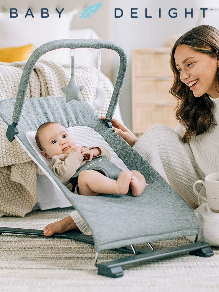 a baby relaxing in the baby delight alpine bouncer seat and a mother sitting next to the bouncer