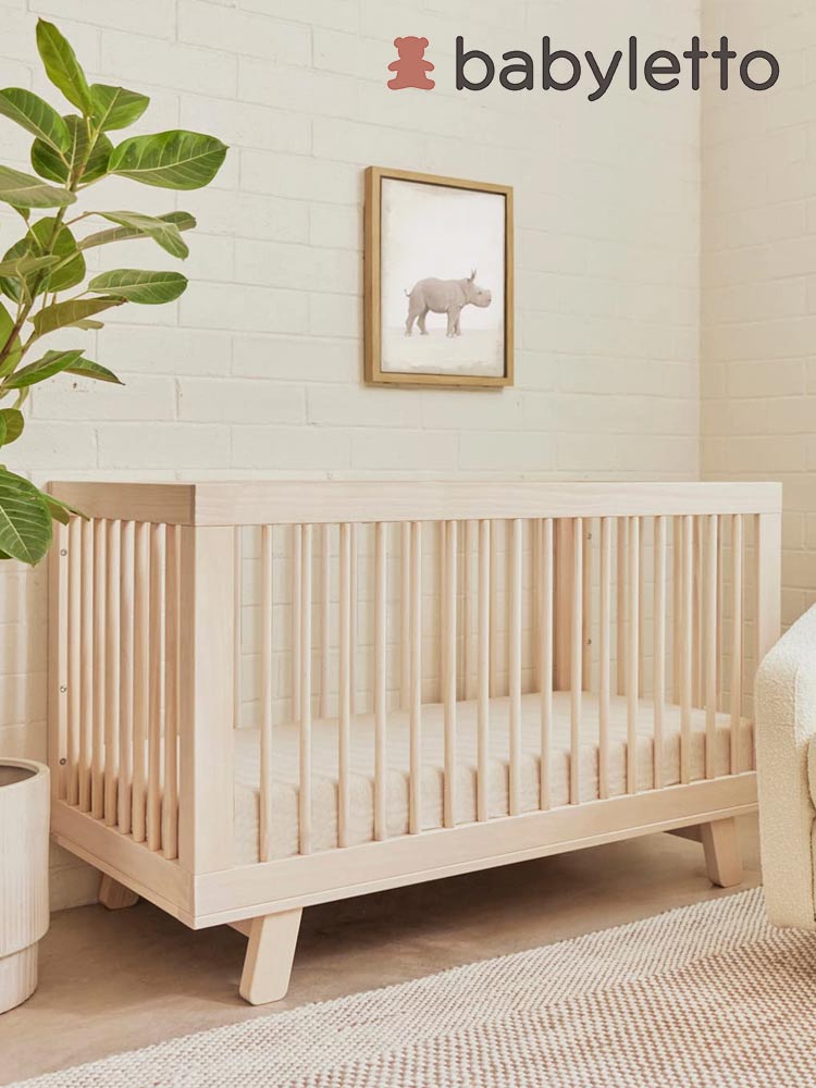 the babyletto hudson crib in a nursery with brick wall and elephant painting on the wall