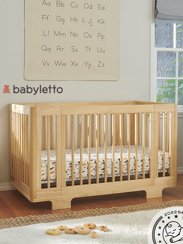a wooden babyletto yuzu crib in a nursery with the alphabet on the wall