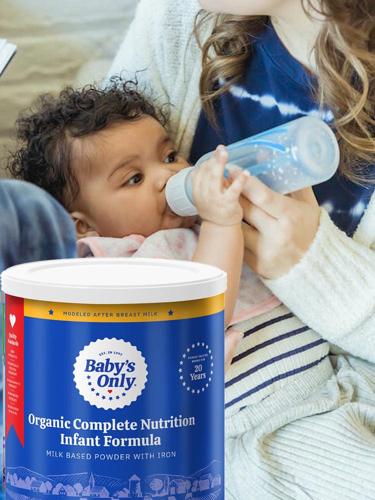 a parent feeding a baby from a bottle filled with prepared babys only premium infant formula