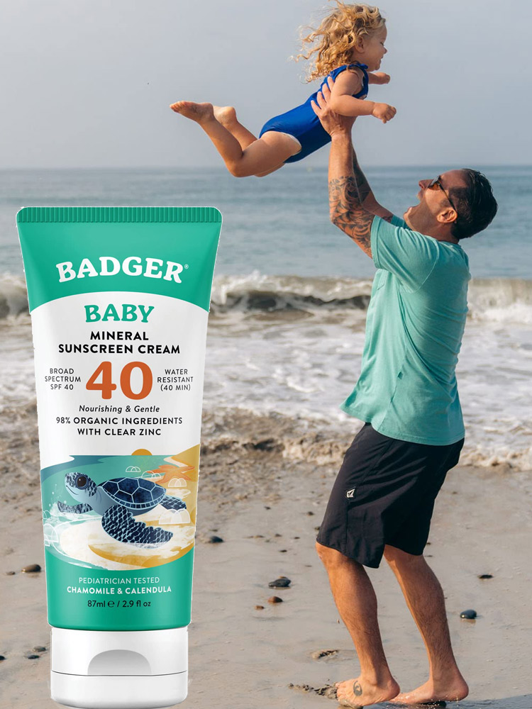 a dad playing on the beach with a toddler girl and a tube of the badger balm sunscreen