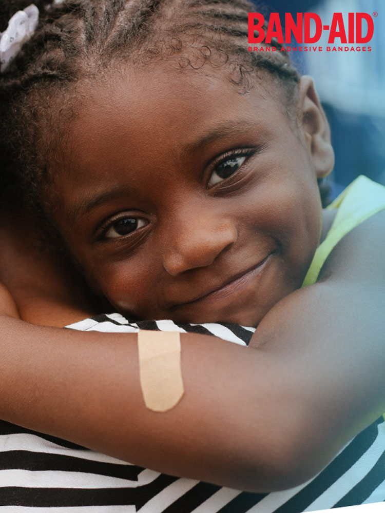 a girl hugging her parent with a band aid water block bandage on her arm