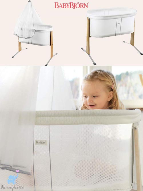 young girl peeking into the baby bjorn bassinet to look at sleeping baby