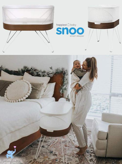 woman standing holding baby above the snoo smart sleeper bassinet