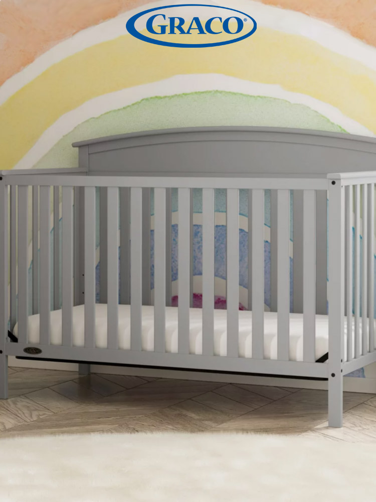 the graco benton crib in a nursery with a rainbow wall painting