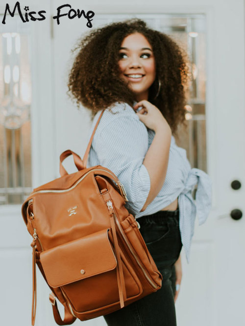 a woman wearing the miss fong diaper bag backpack while smiling