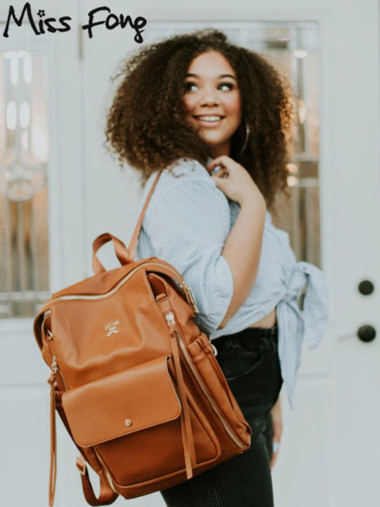 a woman wearing the miss fong diaper bag backpack while smiling