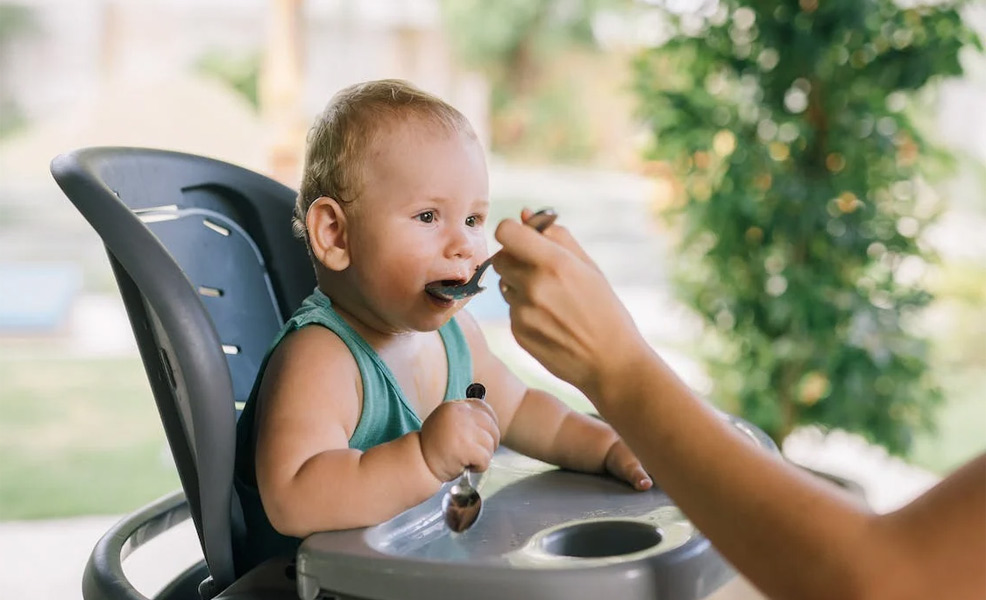 a baby eating fruit and vegetable puree from a spoon