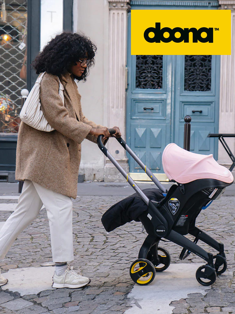 a mother pushing a baby in the doona travel system in an urban environment