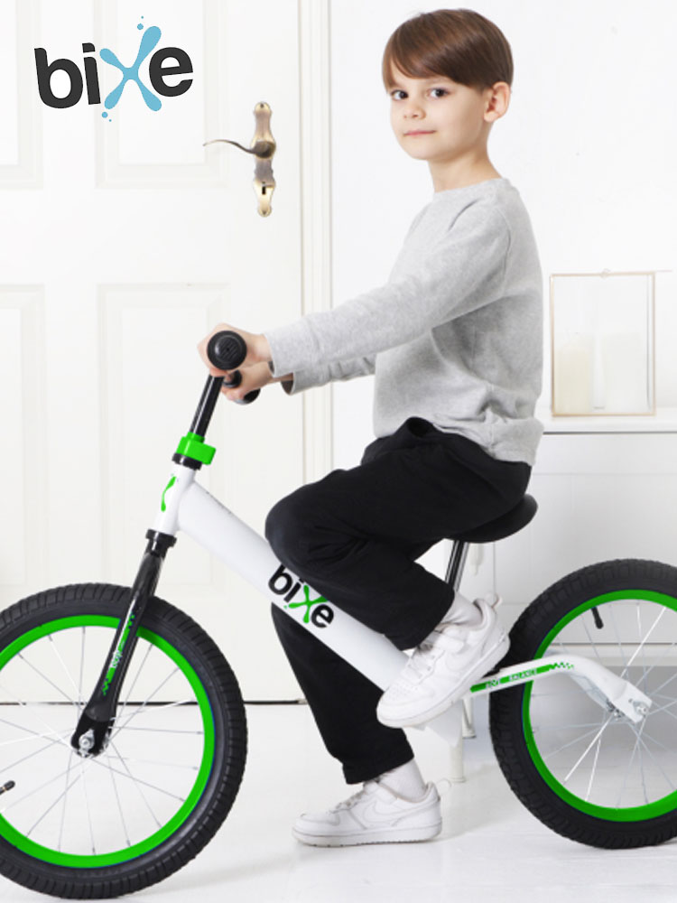 a boy standing beside a bixe bike in a household background