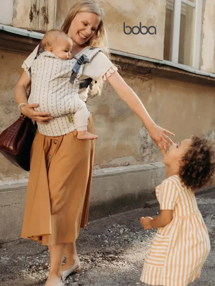 Boba x Baby Carrier worn by a mother walking with a toddler