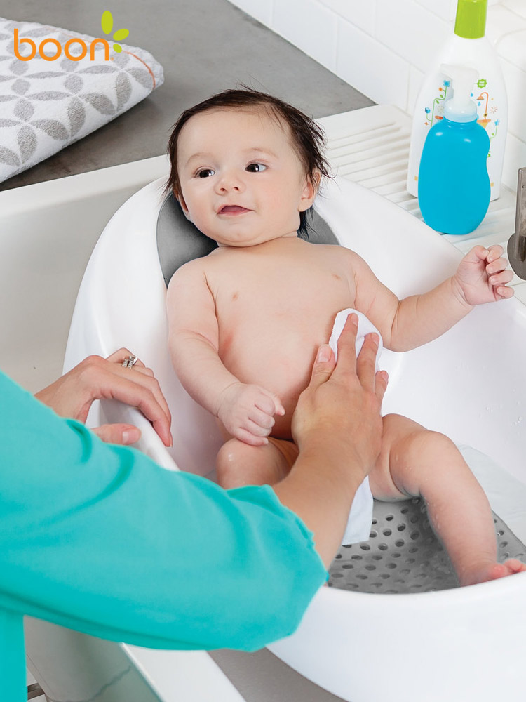 a baby being cleaned in the boon soak bathtub