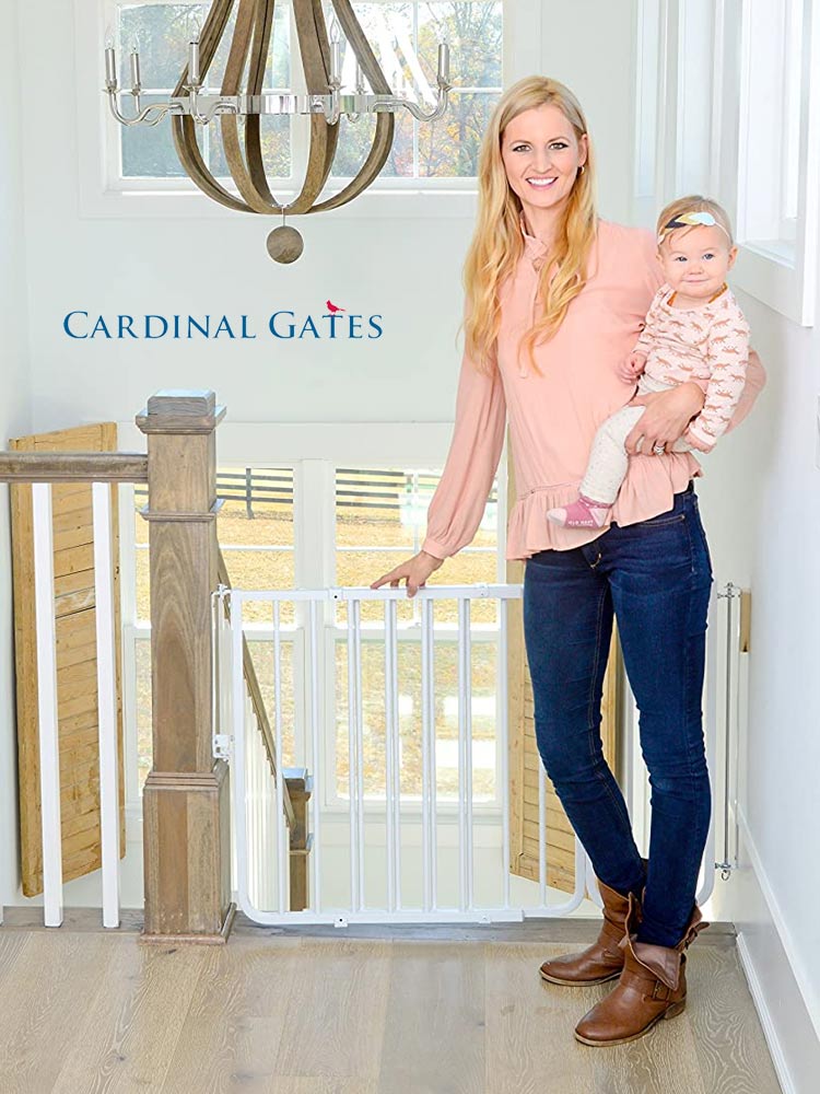 a woman holding a baby while standing in front of the cardinal gate