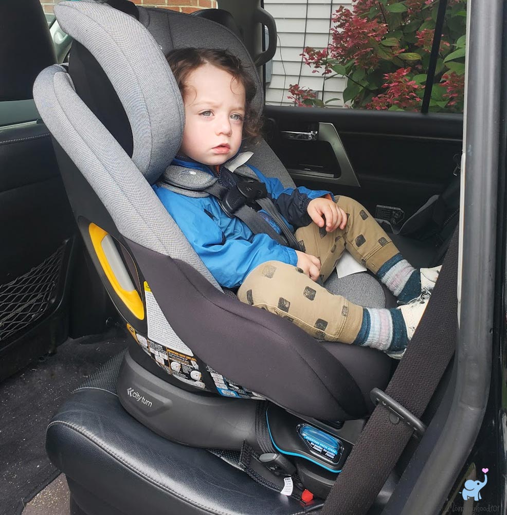 child sitting in the baby jogger city turn car seat installed rear-facing