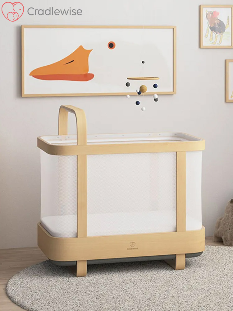 the cradlewise crib pictured in a nursery standing on a small grey rug with abstract art on the wall